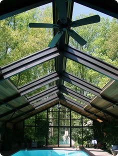 an indoor swimming pool in the middle of a house with a ceiling fan above it