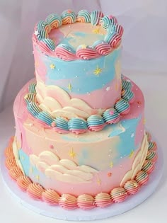 there is a three layer cake with stars and clouds on the top, in pastel colors