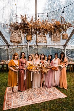 a group of women standing next to each other on top of a rug in front of a tent