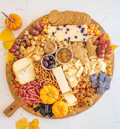 a wooden platter filled with cheese, crackers and nuts