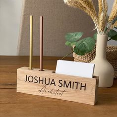 a desk with a pen, notepad and vase on it that says joshua smith