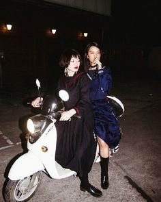 two people sitting on a scooter at night