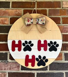 a wooden sign with dog paw prints on it and a bow hanging from the front