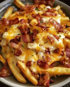 a plate full of french fries covered in cheese and bacon