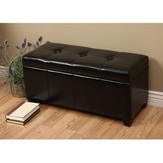 a large black leather storage bench on the floor next to a vase with lavenders