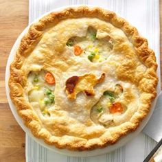 a chicken pot pie on a white plate with a knife and fork next to it