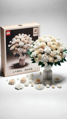 a white vase filled with flowers next to a box