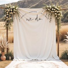 an outdoor wedding ceremony setup with white flowers and greenery on the back of it