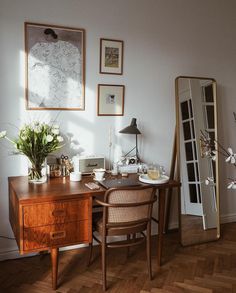 a wooden desk sitting next to a mirror on top of a hard wood floor covered in furniture