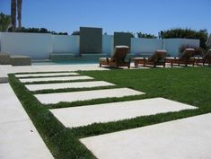 the lawn is lined with stepping stones and grass in front of an outdoor swimming pool