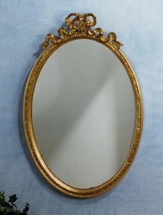 an ornate gold framed mirror hanging on the wall next to a potted green plant