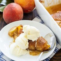 a white plate topped with ice cream next to two peaches and a serving dish