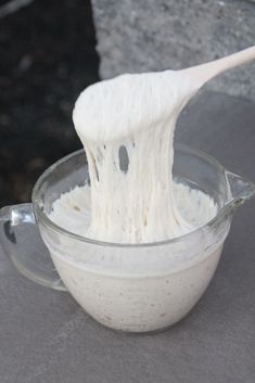 a wooden spoon sticking out of a bowl filled with white batter or powdered sugar