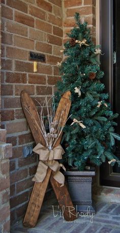 a small christmas tree sitting in front of a brick wall next to a wooden cross