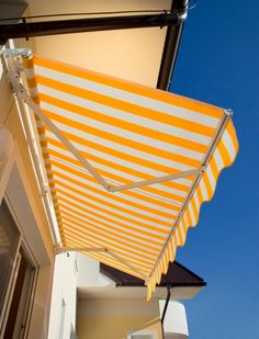 an orange and white striped awning on the side of a building with blue skies in the background