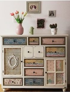 a white dresser with drawers and pictures on the wall