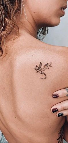 a woman's back with a dragon tattoo on her left shoulder and right arm