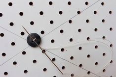 a clock that is on the side of a wall with holes and wires attached to it