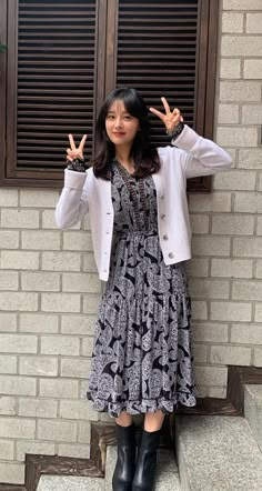 a woman standing in front of a brick wall holding her hands up to the side