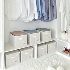 an organized closet with clothes hanging on the wall and shoes in bins next to it