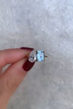 a woman's hand holding an engagement ring with two stones