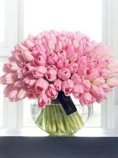 a vase filled with pink tulips sitting on top of a window sill