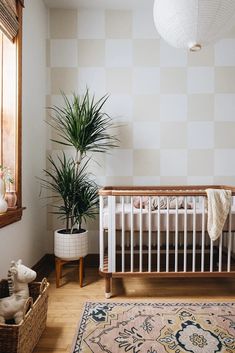 a white crib in a room with a rug and potted plant