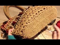 a woman is holding a straw purse on the ground with beads and yarn around it