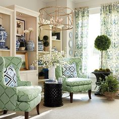 a living room filled with green chairs and vases next to a window covered in curtains