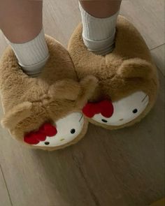 a person wearing hello kitty slippers on top of a wooden floor with their feet in the air