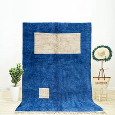 a blue area rug with two square patches on it and a plant in the corner