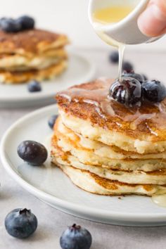 someone is pouring syrup on some pancakes with blueberries