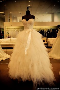 a dress on display in a store with other wedding gowns behind the mannequin