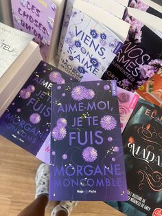 there are many books on the table with flowers in front of them and one is purple