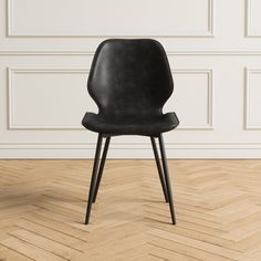 a black chair sitting on top of a hard wood floor next to a white wall