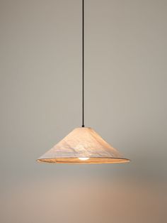 a light fixture hanging from a ceiling with a white wall behind it and a black cord