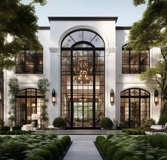 a large white house with lots of windows and plants in the front yard at night