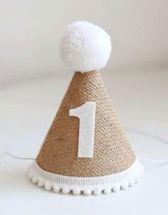 a burlap hat with a white number one on it and a pom - pom at the top