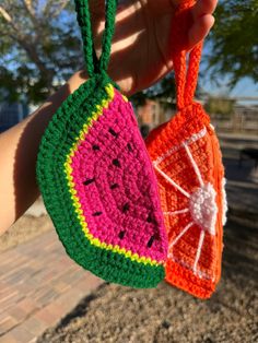 two crocheted watermelon purses hanging from a string in front of a tree