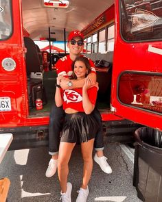 a man and woman sitting on the back of a red bus with their arms around each other