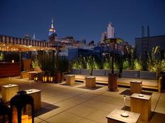 an outdoor seating area with benches and lights on the top of buildings in the background