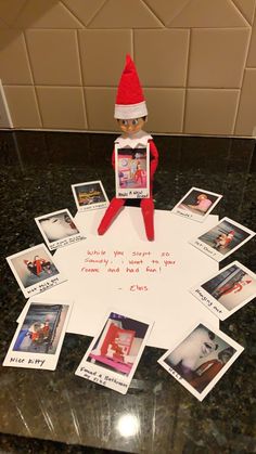 an elf sitting on top of a table next to pictures and postcards with words