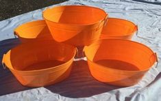 four orange buckets sitting on top of a white sheet