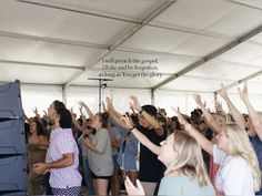 a group of people standing under a tent with their hands in the air