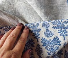 someone is stitching fabric with their hands on the back of a blue and white chair