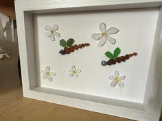 a white frame with flowers and leaves in it