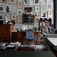 a room filled with lots of books and pictures on the wall above a chair in front of a desk