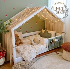 a child's bed with lights and teddy bears on the floor in front of it