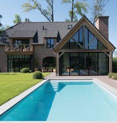 a house with a pool in front of it and a large lawn area next to it