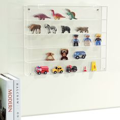 there are many toy animals on the shelf in front of this bookcase, which is also mounted to the wall